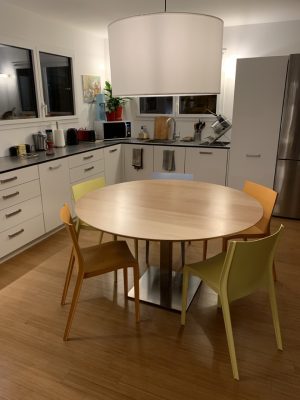 Grande table dans une cuisine. Plateau en bois et pied en métal.